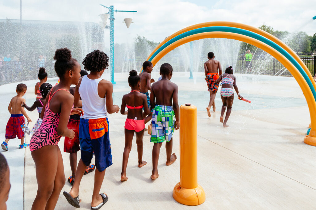 A group of kids run through a splash park.