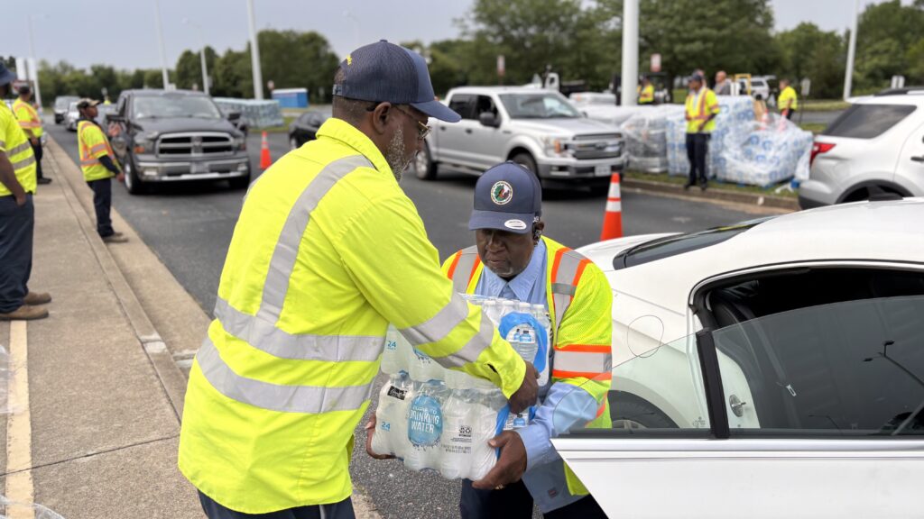 Workers carry cases of bottled water at Harvie Elementary School