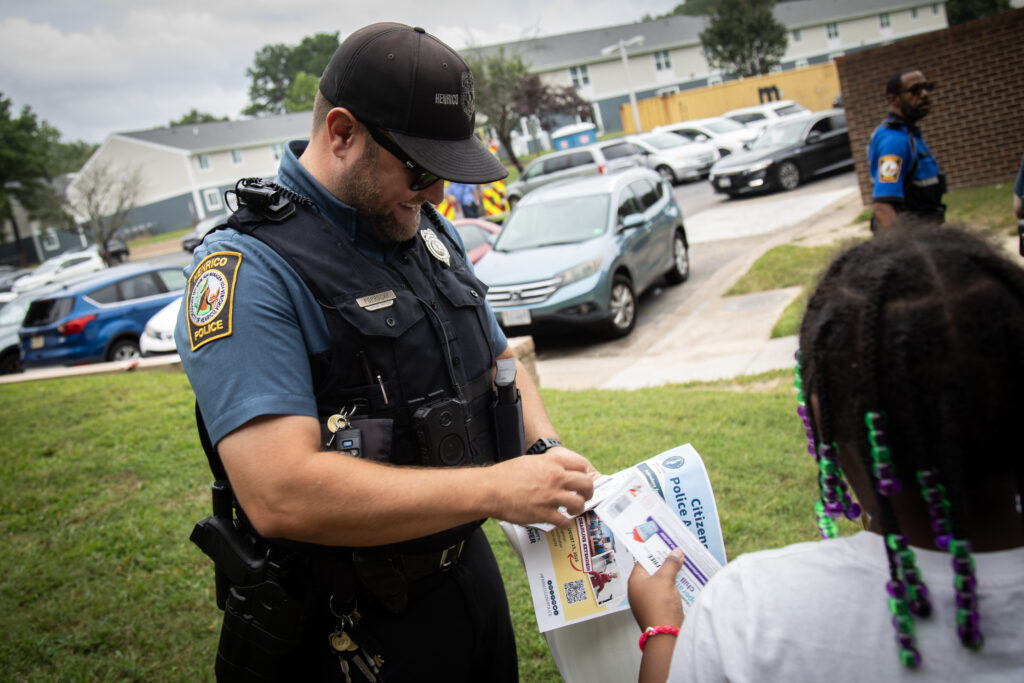 Henrico Police officers smiles as he hands a young girl slushie coupons.