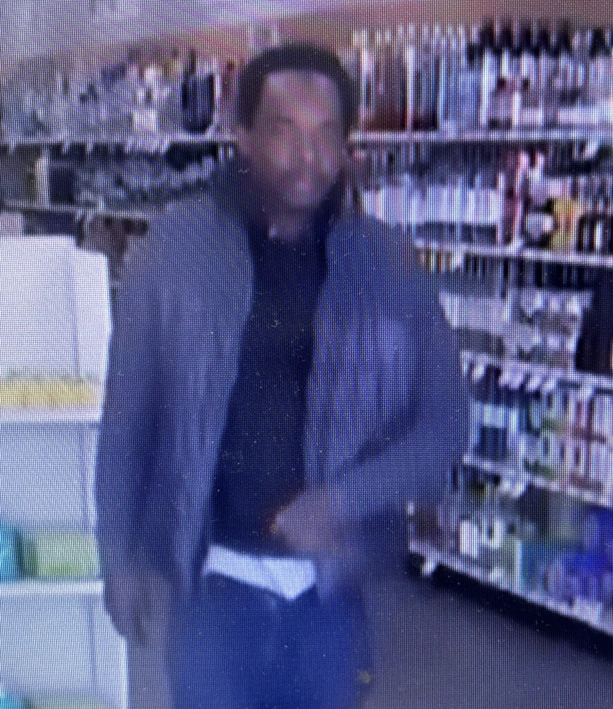 This image shows a black male in a gray sweatshirt and black shirt inside am ABC store.