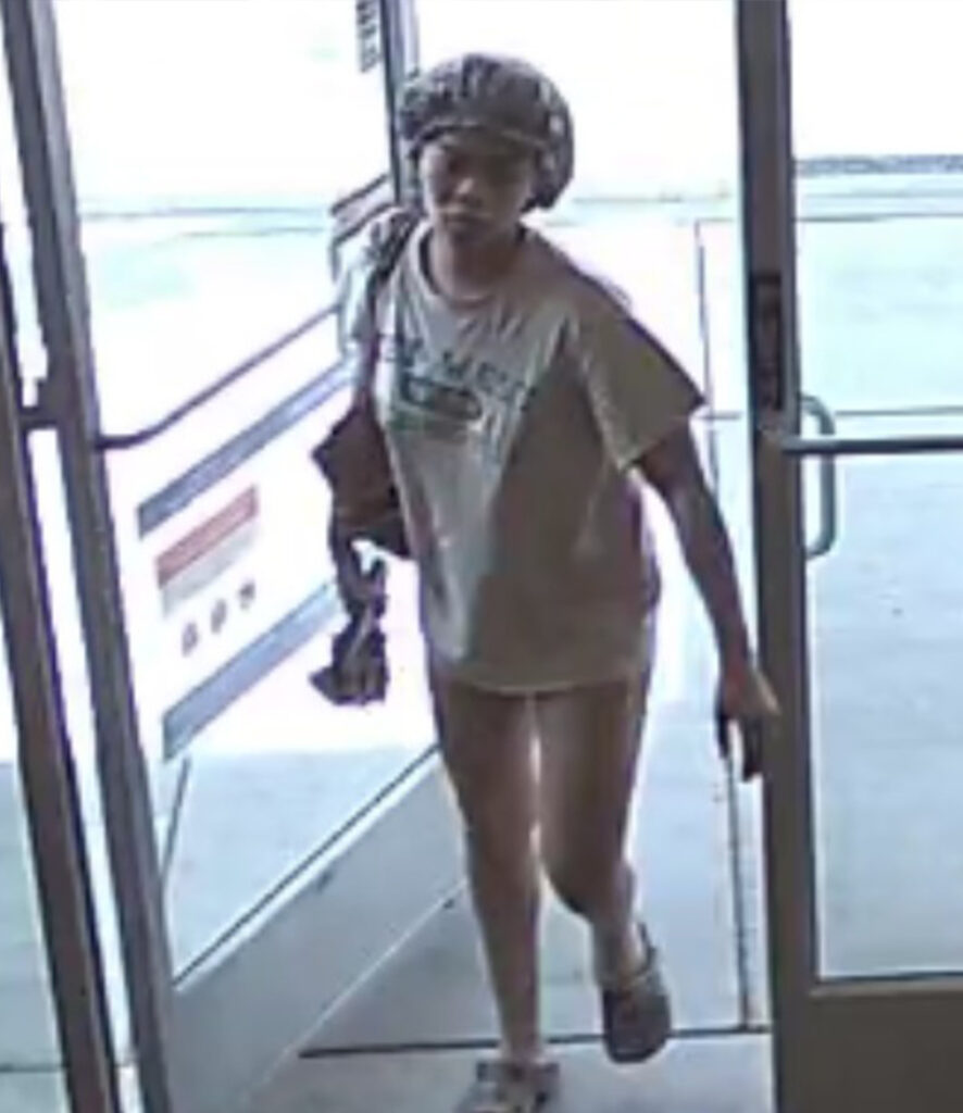 Image shows a woman in a bonnet and short sleeve shirt entering a business.