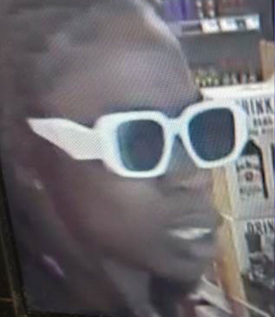 A close up surveillance photo of a person wearing white sunglasses.