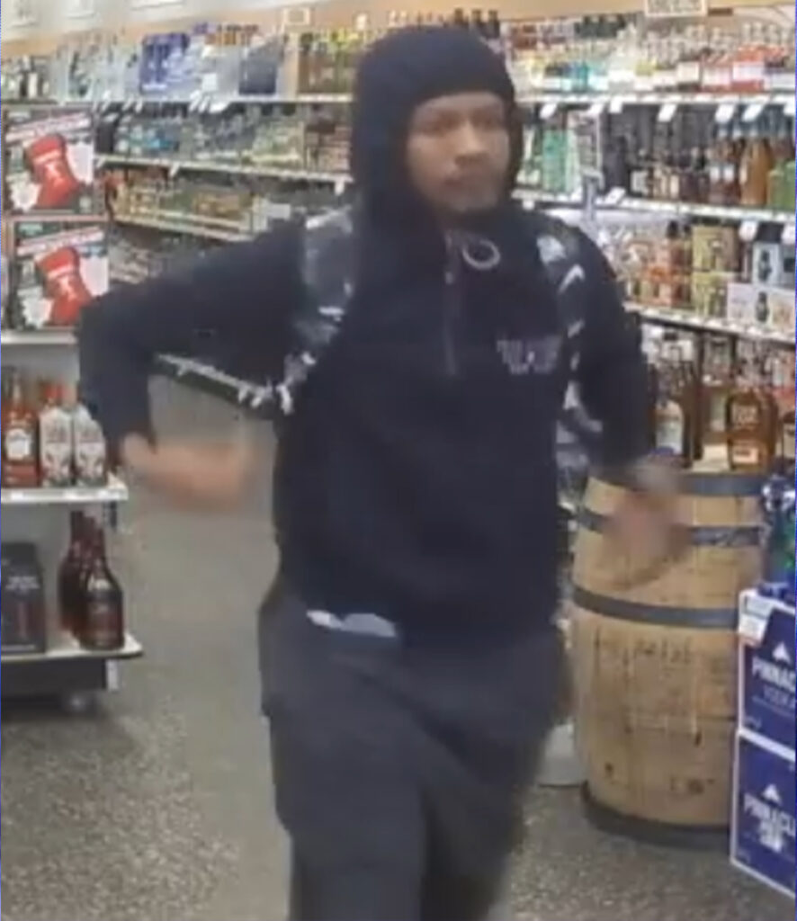 A man wearing a hooded sweatshirt in an ABC Store. 