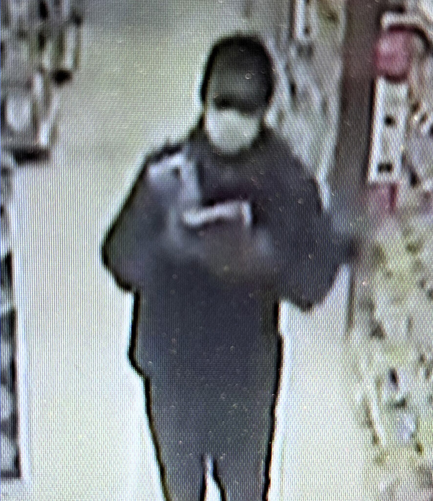 A blurry image of a man wearing a facemask in an ABC store. 
