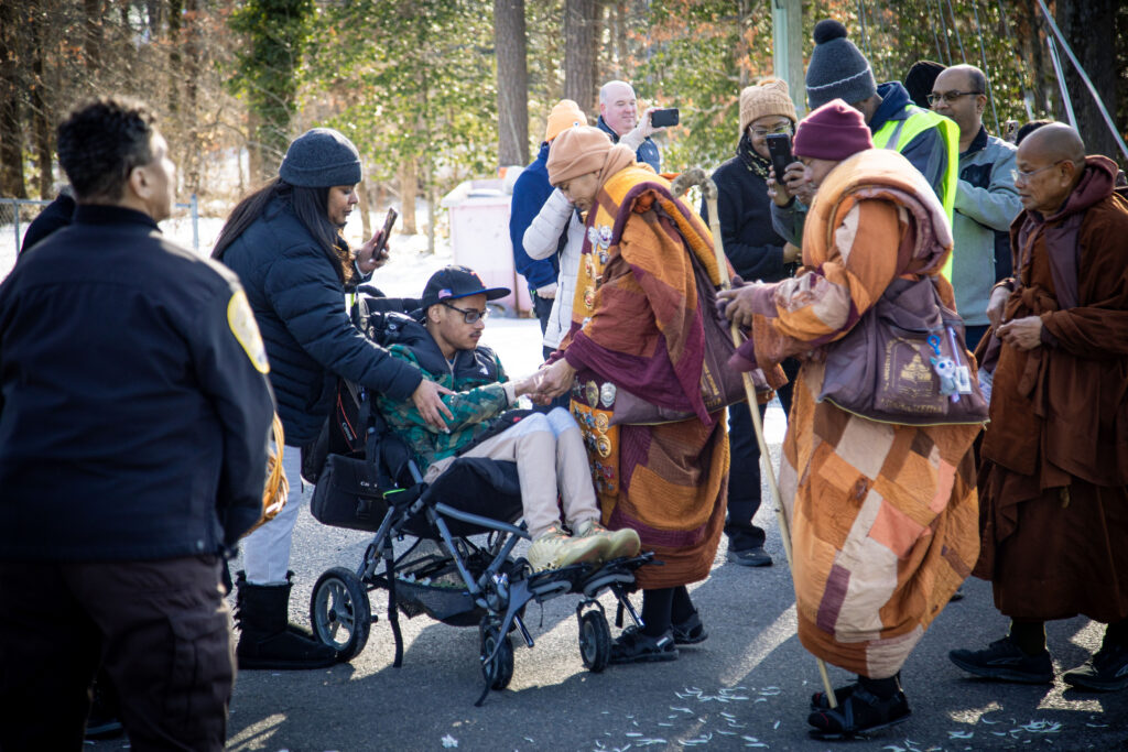 A photo of a monk blessing a man in a wheelchair.