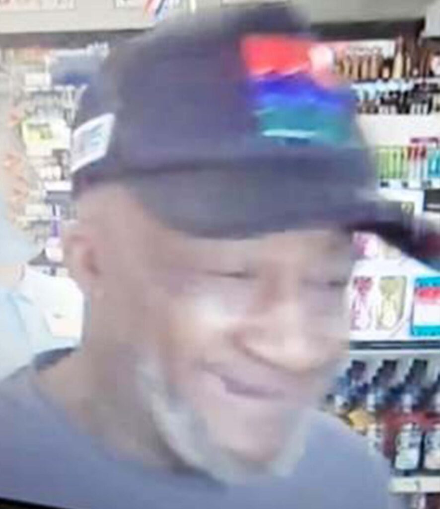 A person wearing a hat with red blue and green markings on it, inside a Virginia ABC Store.