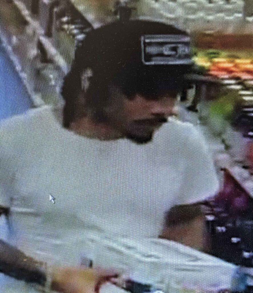 A man wearing a dark colored hat with a logo on it in an ABC Store.