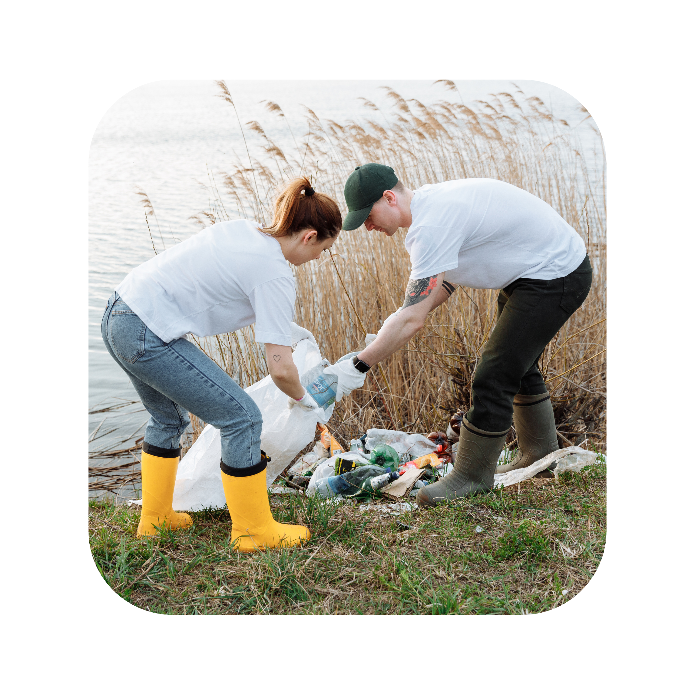 photo of a man and a woman cleaning up a pile of litter in the grass alongside a river