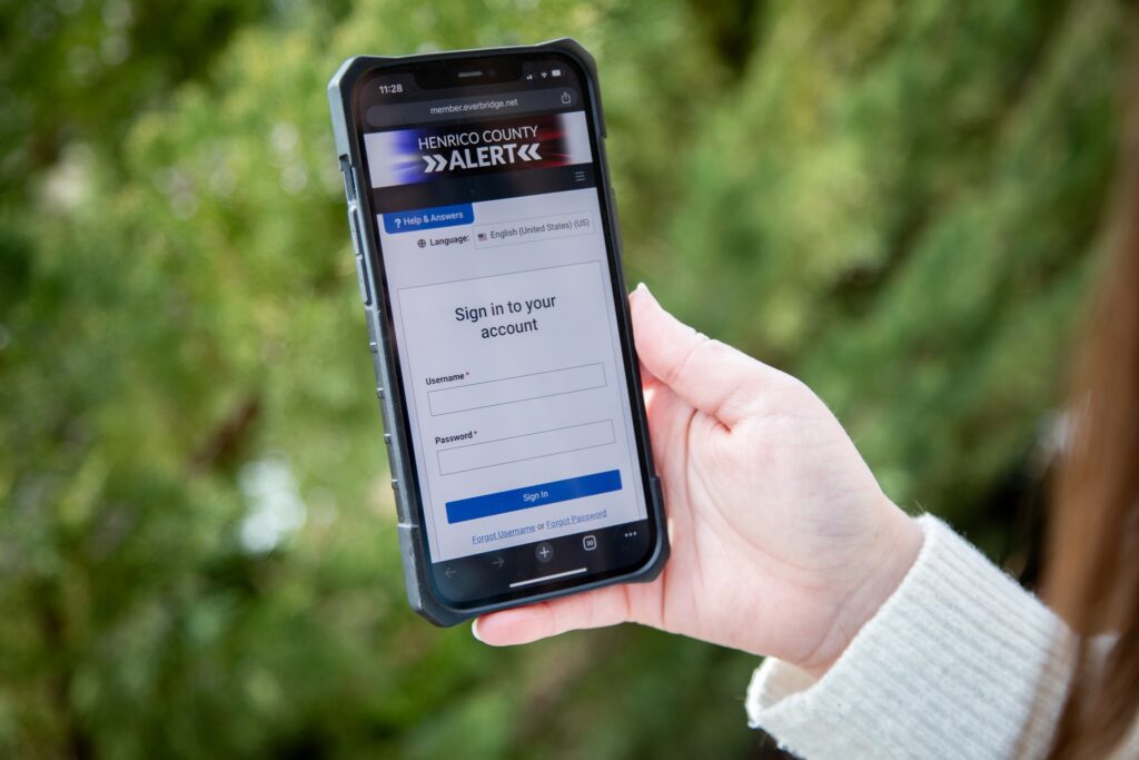 Person holding a phone showing the Henrico Alert login page