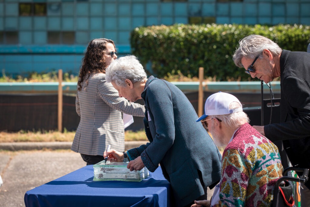 A woman signs a glass block.
