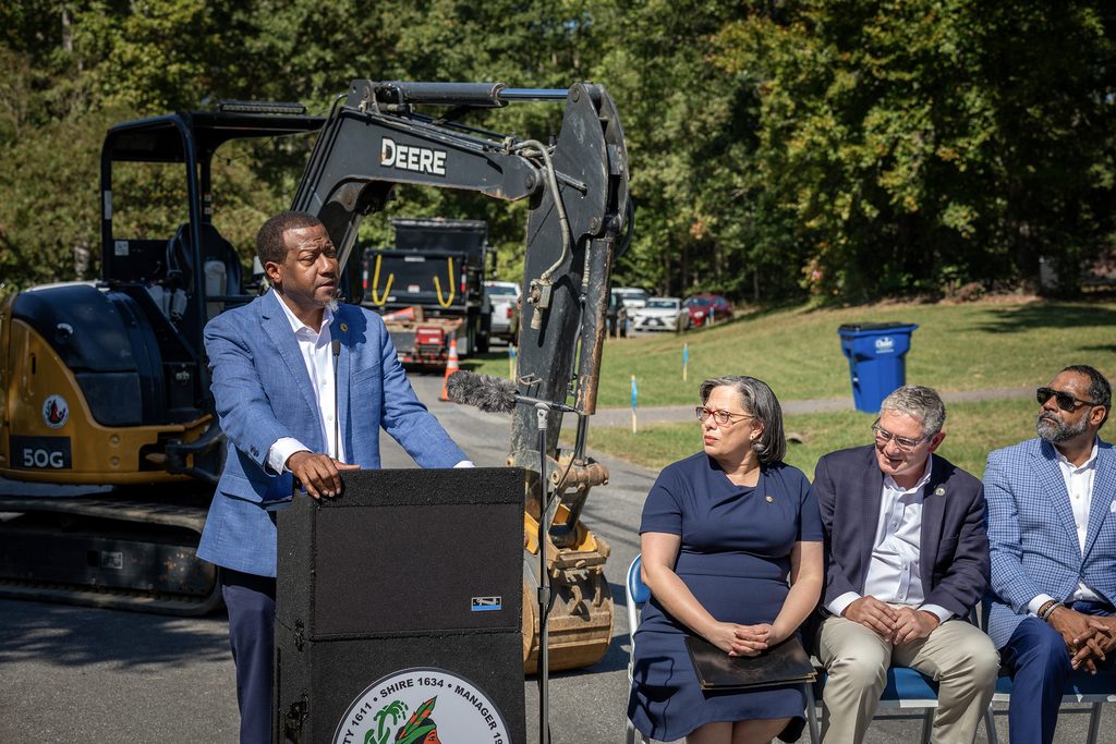 Varina District Supervisor Tyrone Nelson speaks at the lectern as U.S. Rep. Jennifer McClellan, County Manager John Vithoulkas and Board Chair Roscoe Cooper watch from chairs next to it.