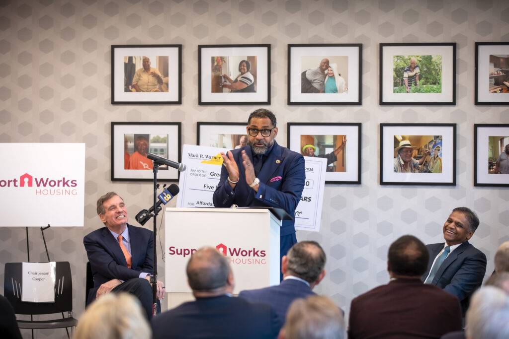 Board of Supervisors Chair Roscoe D. Cooper III applauds while speaking to an audience.
