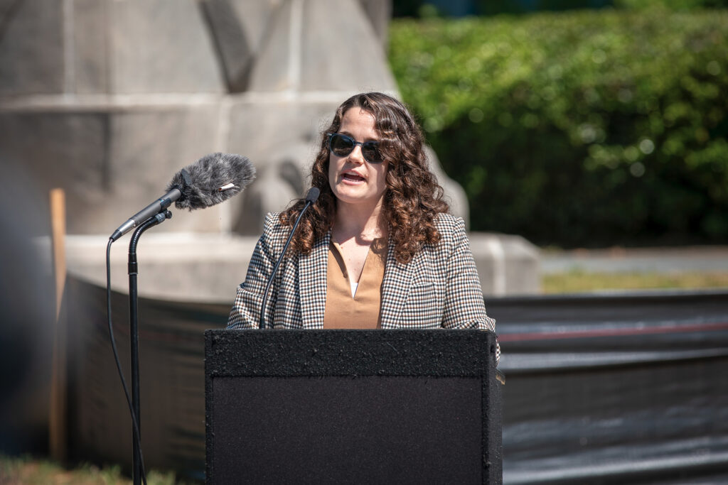 An official speaks at a lectern at an outdoor event.