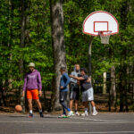 A group of people laugh while they play basketball.