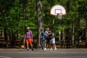 A group of people laugh while they play basketball.
