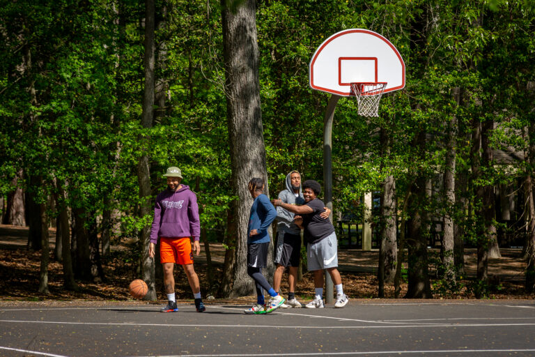 A group of people laugh while they play basketball.