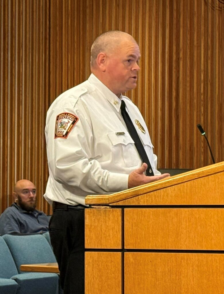 A fire official speaks at a lectern in a meeting room.
