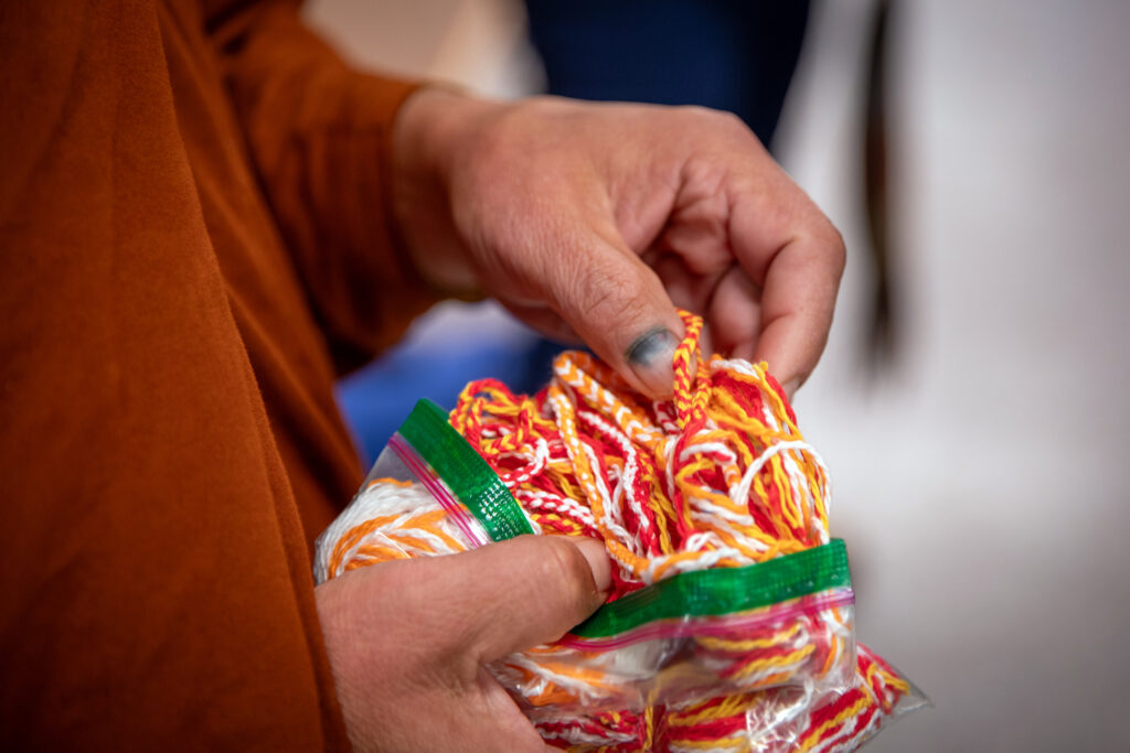 A monk holds a bag of braided bracelets.