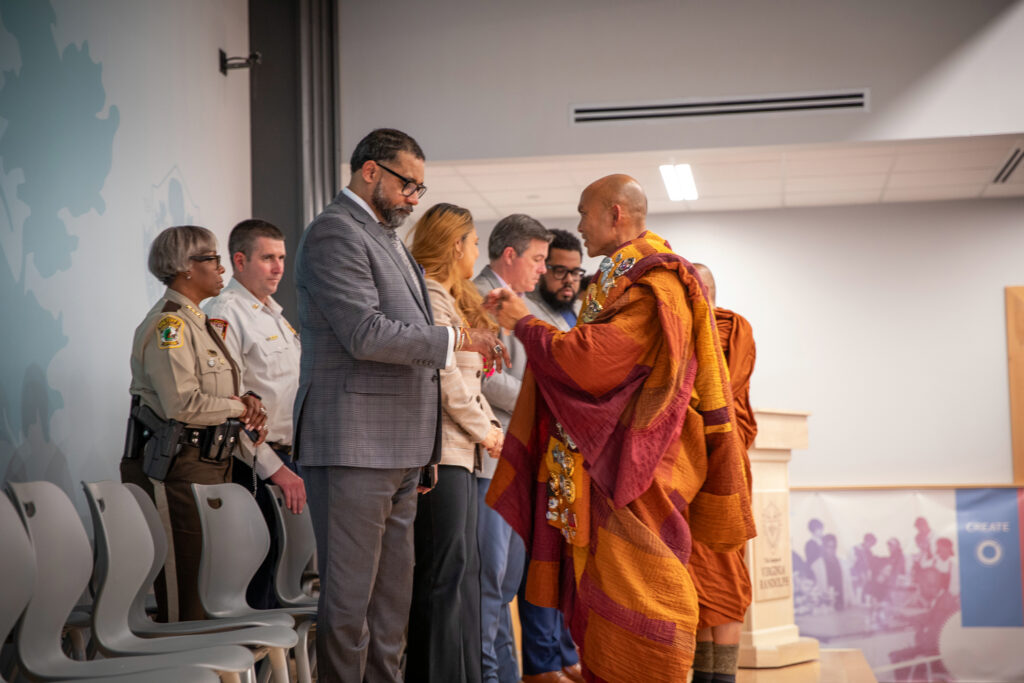 Two monks tie braided peace bracelets onto the wrists of the Henrico Board of Supervisors.