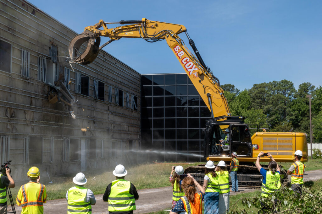 An excavator approaches a vacant building.