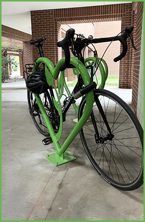 A bike chained to a bright green, heart shaped bike rack.