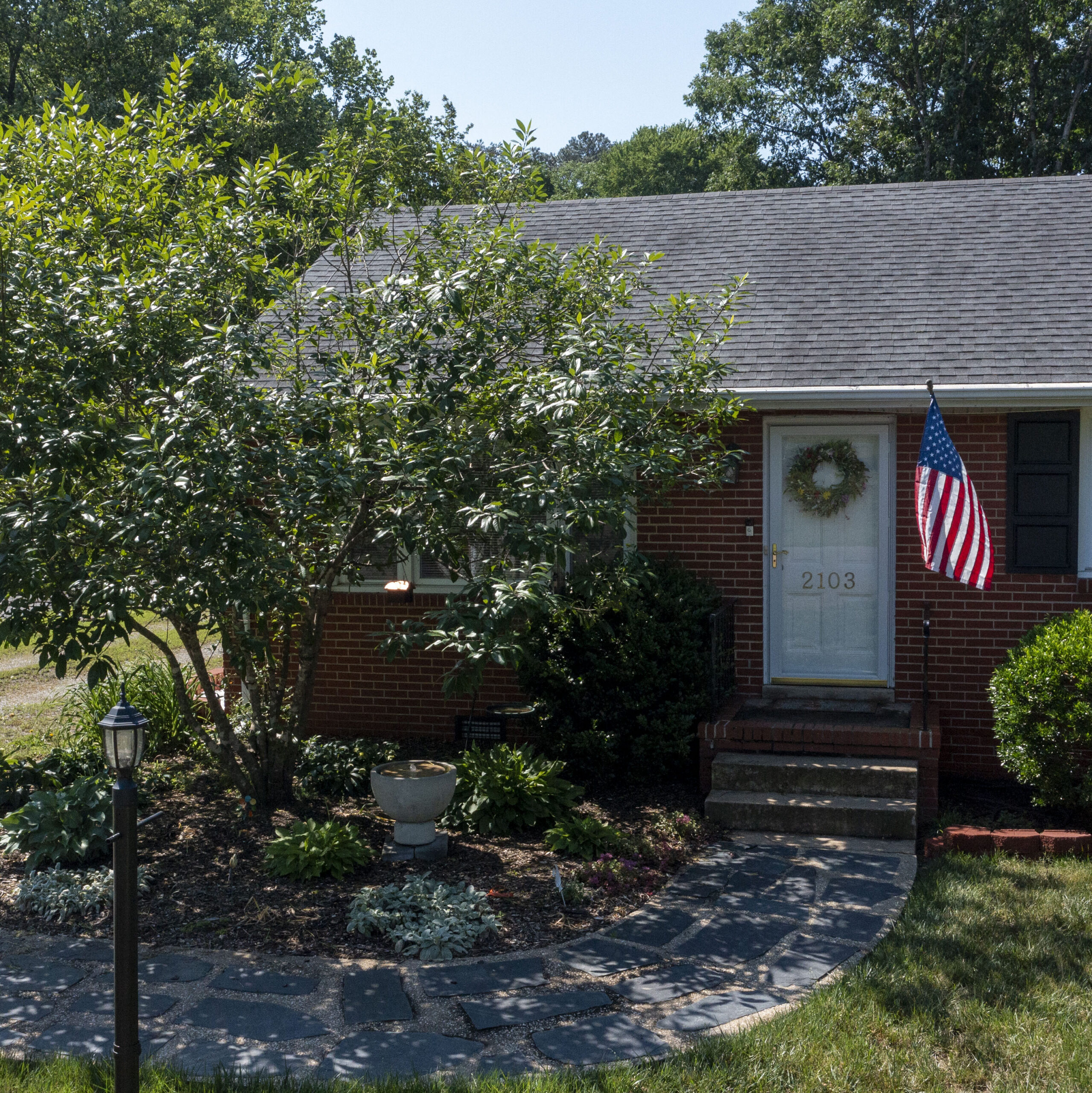 A brick house with a small garden sitting to the left of the front door.