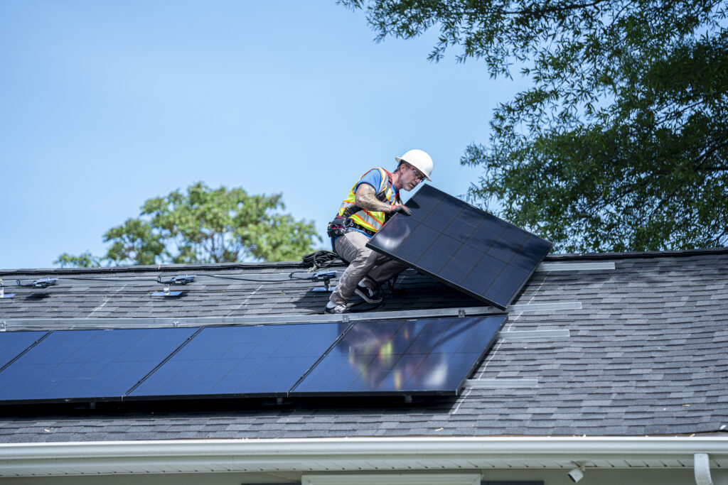 A photo of a man on a roof installing solar panels.
