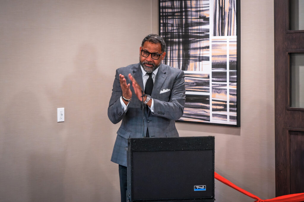 A man in a suit speaks at a lectern before a ribbon-cutting ceremony