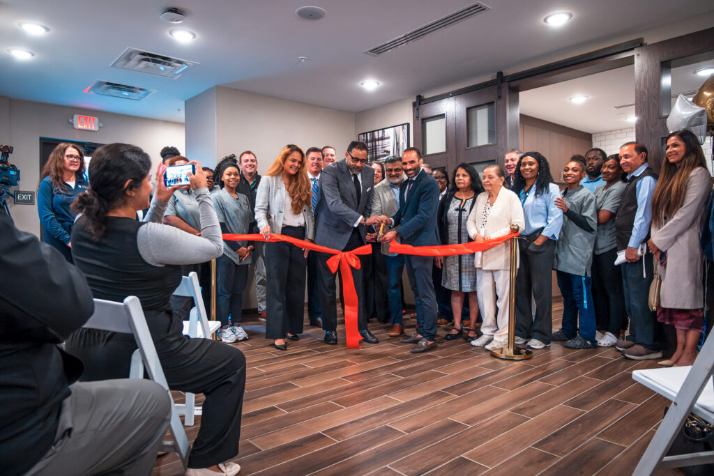 Officials prepare to cut a red ribbon to celebrate the opening of a hotel.