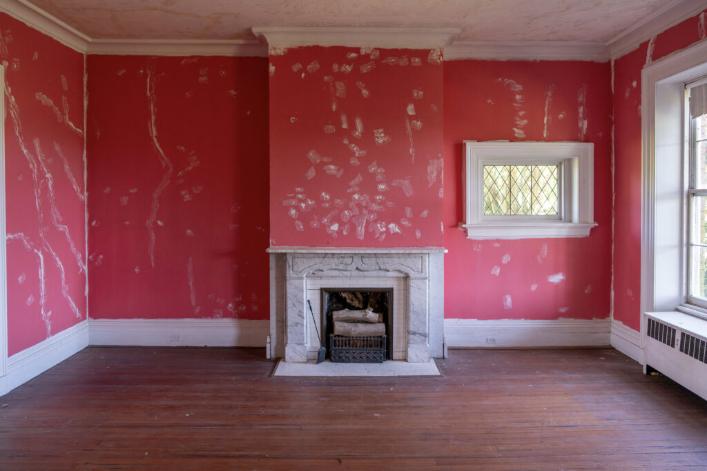 A fireplace in a historic home with pink walls.
