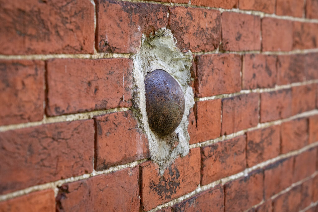 A cannonball is stuck in a brick wall of a home.