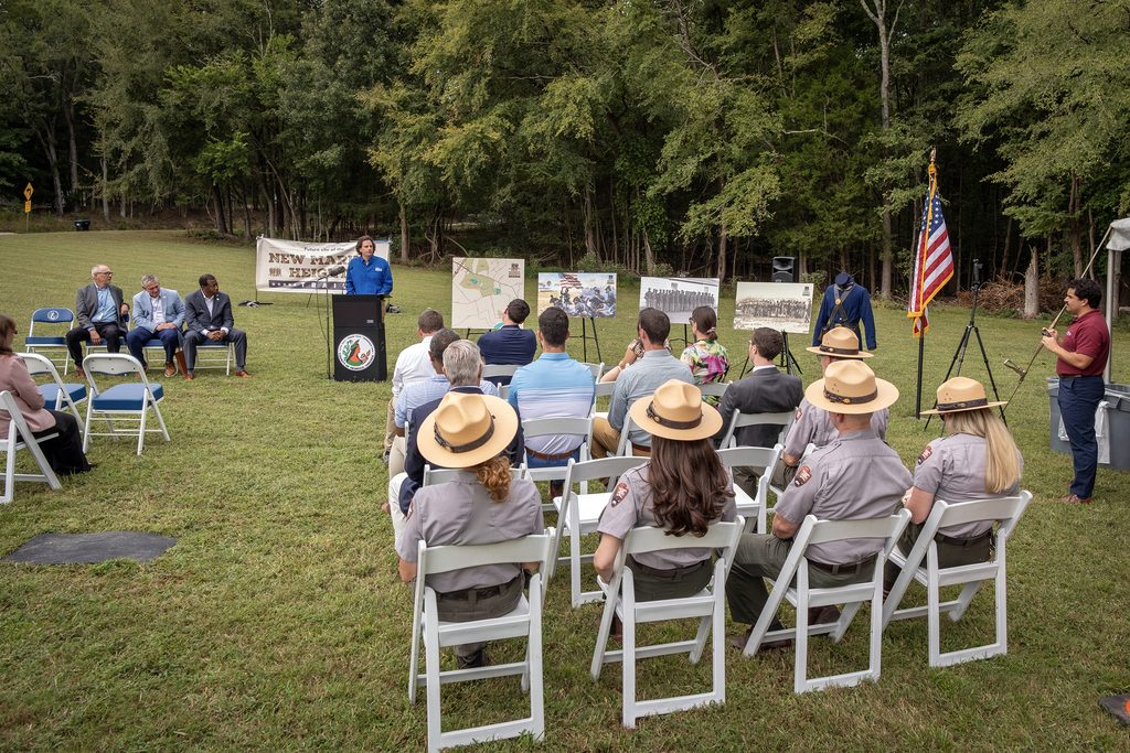 Dr. Joe Rizzo speaks at a lectern in front of a crowd of people.