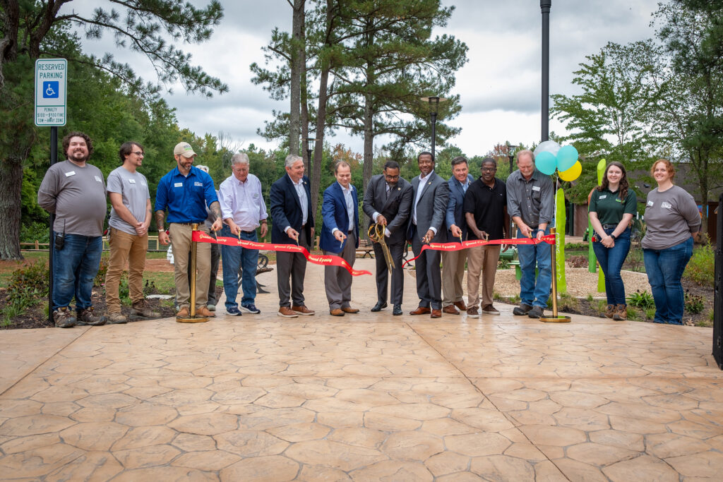 10 adults stand in a row to cut a red ribbon.