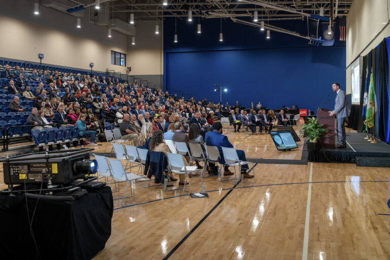Deputy county manager speaks at lectern before an audience at the State of the County address.