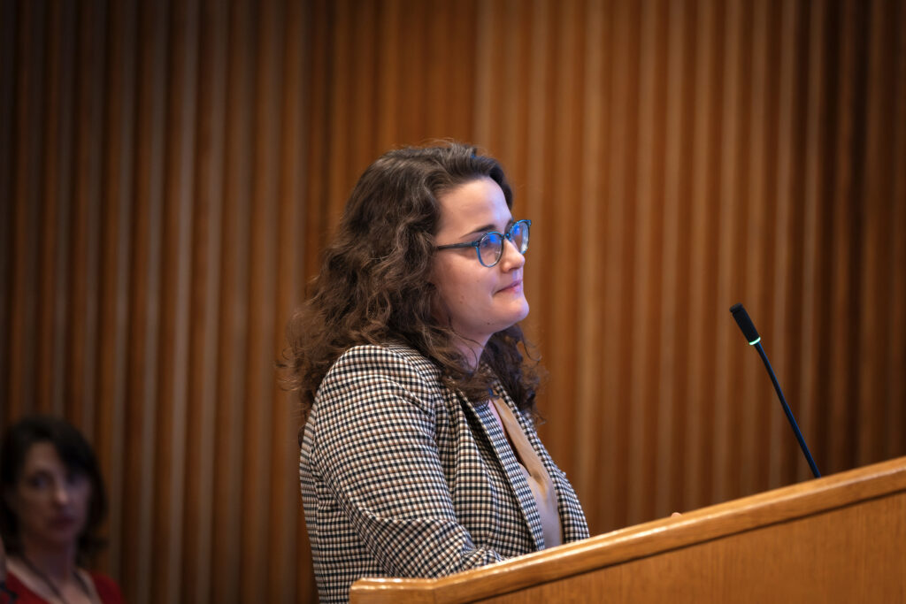 A woman smiles at a podium.