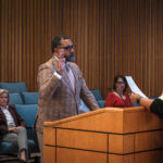 A man holds his hand in the air while taking an oath.