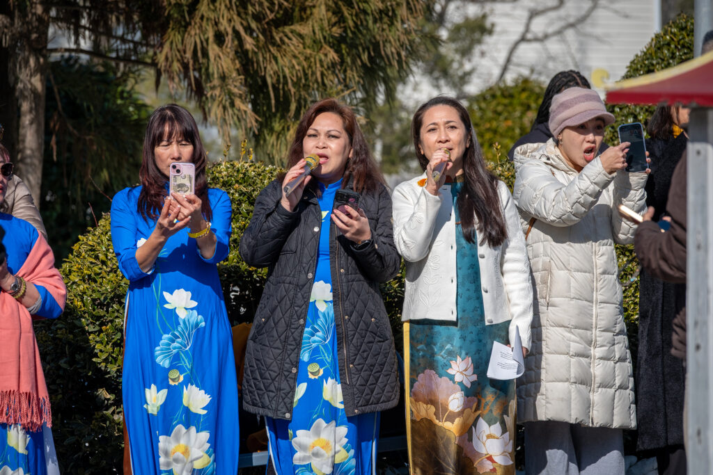 Three woman stand in blue silk dresses.
