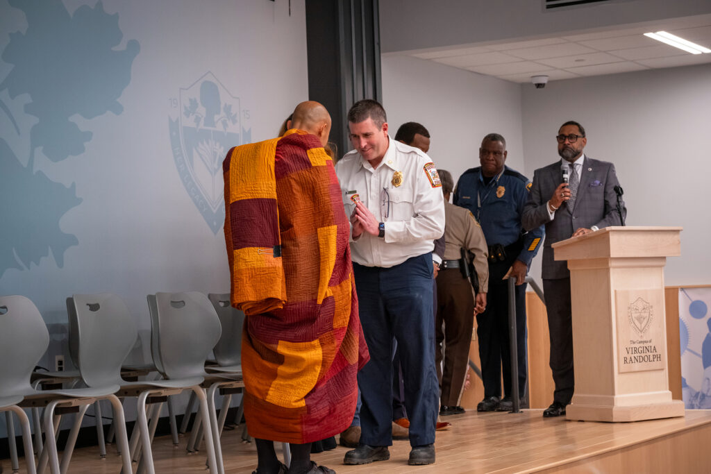 A fire chief gives a monk a Henrico Fire Division patch.