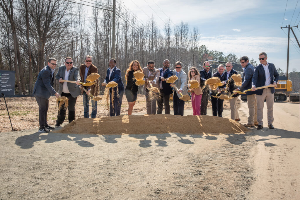 Officials toss sand at a groundbreaking event.