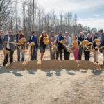 Officials toss sand at a groundbreaking event.