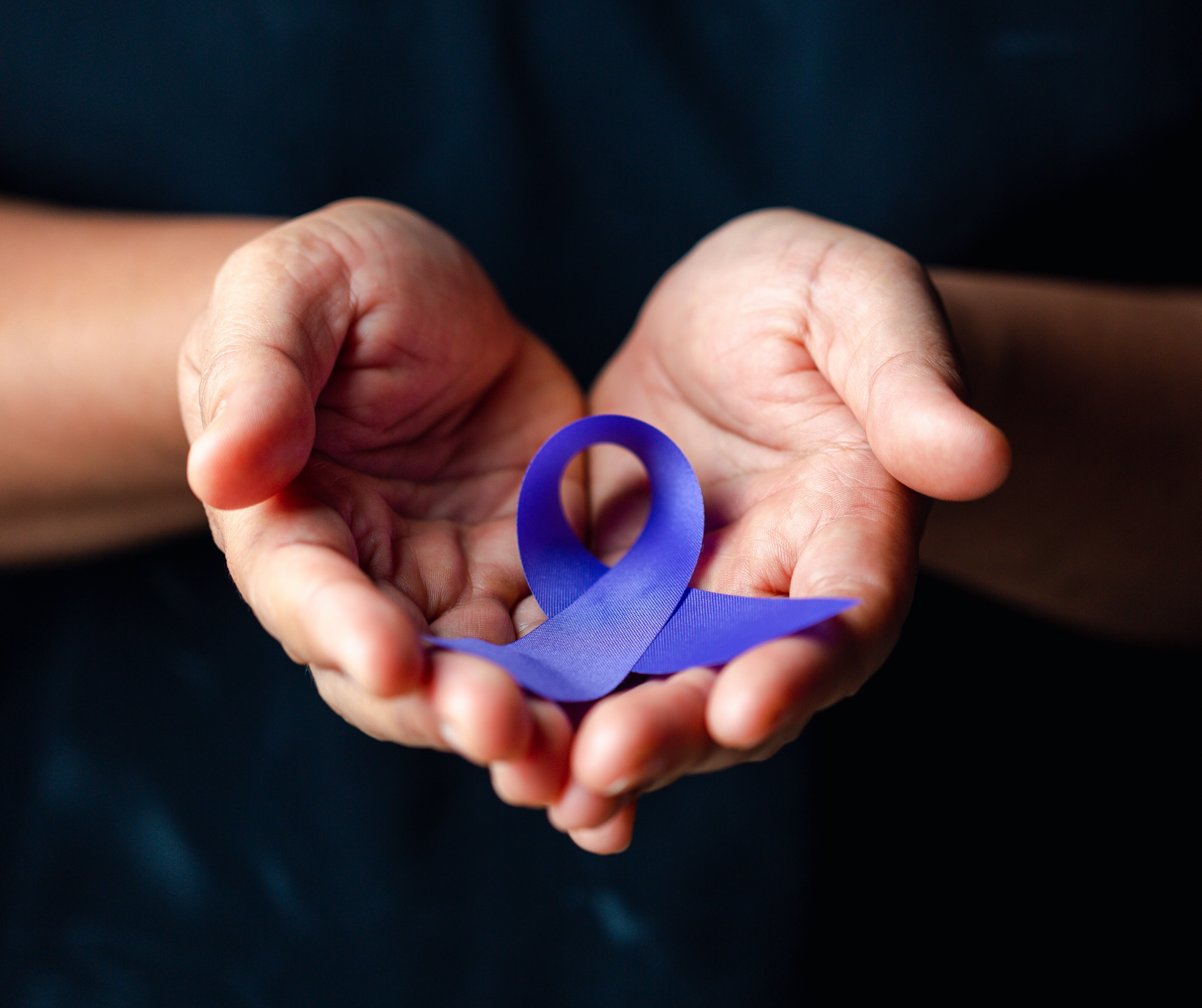 Someone holding a purple ribbon in honor of Domestic Violence survivors and victims.
