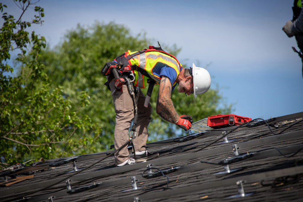 A construction worker installs solar panels on a roof.