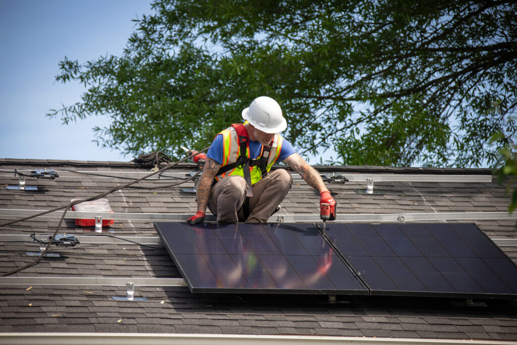 A construction worker installs solar panels on a roof