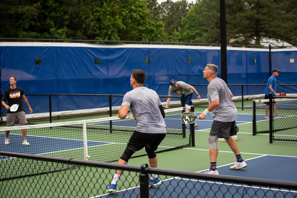 A photo shows a group of people playing pickleball outside.