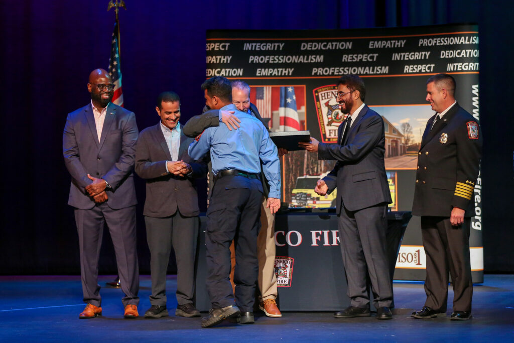 A firefighter receives a congratulatory hug from an official during a graduation.