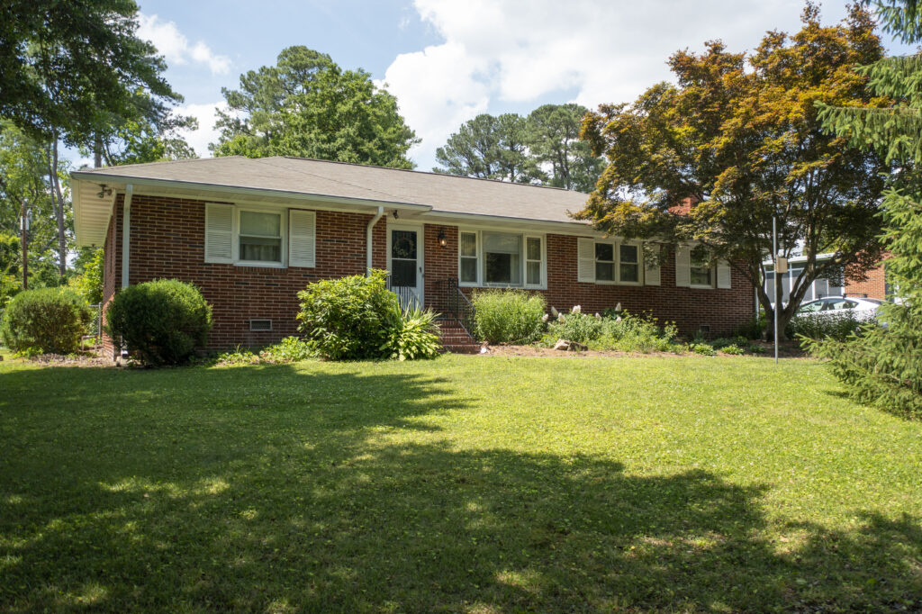 photo of a house with shrubs in front and a well-maintained front yard