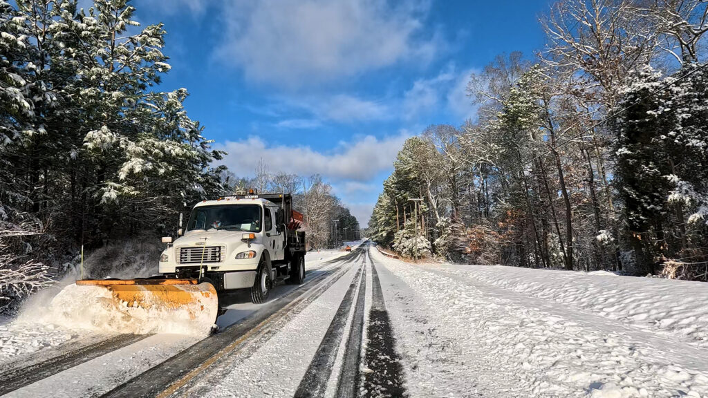 A snow plow clears snow from a road.