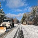 A snow plow clears snow from a road.