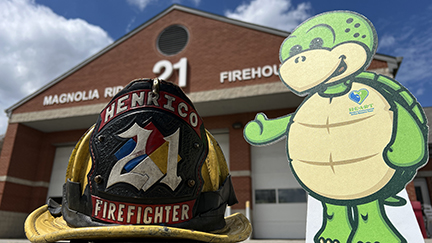 Stewart mascot next to fire helmet in front of fire station 21.