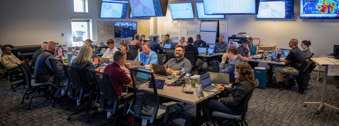 photo of people from different agencies around emergency operations center tables